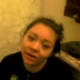 A girl is video-recorded by her friend as she pees while sitting on a toilet.